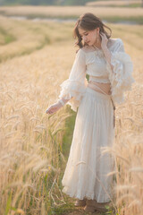 Fototapeta na wymiar Beautiful Asian women were in white dresses relaxed and happy in the Barley rice field season golden color of the wheat plant. Freedom traveler, dreamy portrait in a wheat field.