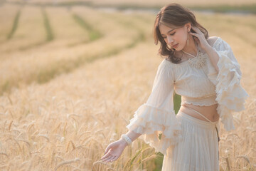 Fototapeta na wymiar Beautiful Asian women were in white dresses relaxed and happy in the Barley rice field season golden color of the wheat plant. Freedom traveler, dreamy portrait in a wheat field.