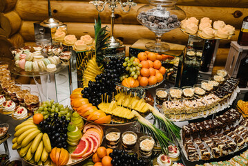 Candy bar. Fresh, exotic fruits, light snacks on a buffet table. Assorted mini delicacies and...