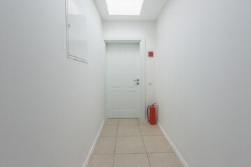 Apartment door at the end of the corridor with fire extinguisher