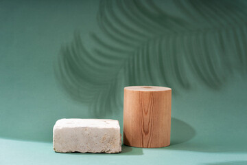 Composition empty podium material wood and stone geometric shape. Product presentation. Pastel green background and shadows of tropical leaves. Beautiful background from natural materials.