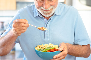 Bearded senior caucasian man holding a ready to eat fruit salad with kiwi banana strawberries and...