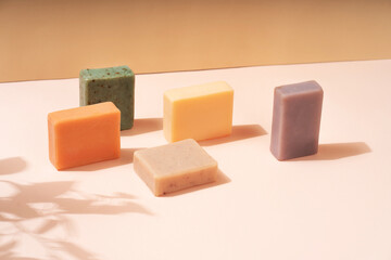 Natural handmade soap in different sizes and colors. Brown background shadows of flowers from the sun. Cosmetic pedestal for product promotion.