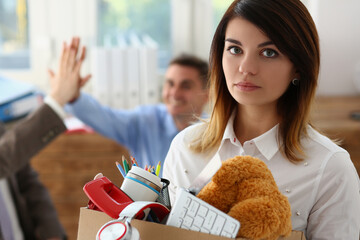 Sad dismissed woman against background of joyful colleagues partners in office