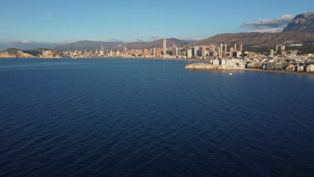 Aerial view of Benidorm and the mountains range inland. Panning right while ascending.