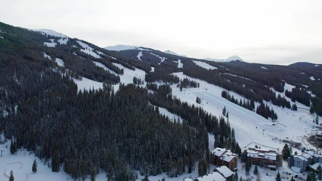 Aerial drone shot of ski slopes on a mountain with skiers and snowboarders