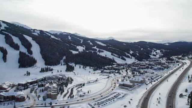 Drone fly over of a ski resort with busy roads next to the highway