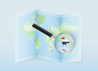 A folded world map with a magnifying lens pointing towards Thailand. Map and flag of Italy in loupe.