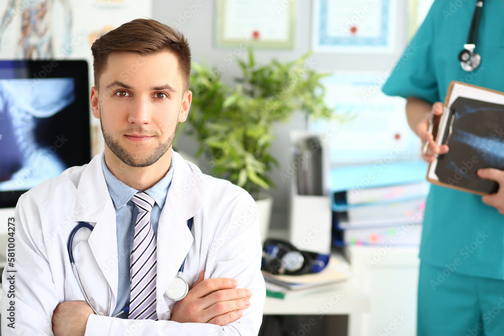 Wall mural portrait of a young doctor in a clinic with an assistant