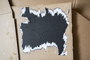 Ripped black square paper on cardboard background