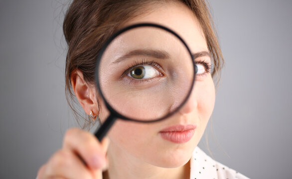Inquisitive young woman looking through magnifying glass