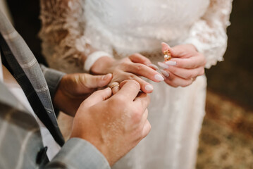 Engagement. The handsome groom wears a golden ring on the finger of the attractive bride. Newlyweds. Ceremony in the church on the wedding day. Hands with wedding rings. Closeup. Top view.