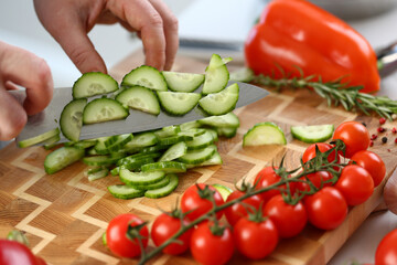 Cutting vegetables with knife for cooking on board