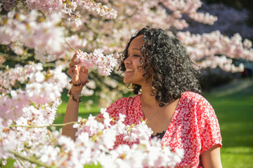 Fototapeta premium metis woman smelling the scent of cherry blossoms in spring