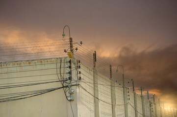 Prison security electric fence and high concrete wall. Prison high voltage fence. Barbed wire...