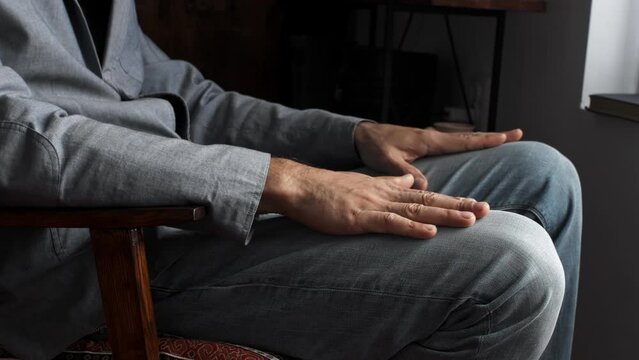 A man rubs his knees with his hands at home. Pain and irritation