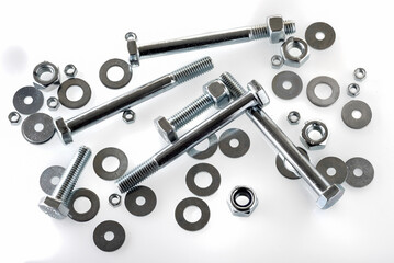 Bolts, nuts, screws and washers scattered on white background in top view