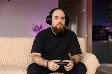 Male playing on PlayStation with the controller in his hands and with headsets on. Face expression...
