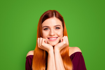 Portrait of red straight-haired attractive cute nice happy smiling young girl, chin on hands. Isolated over bright vivid yellow background