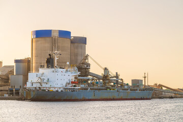 Commercial cement carrier at Port Adelaide docks viewed across the Port River at sunset, South...