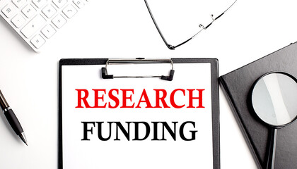 RESEARCH FUNDING text written on paper clipboard with office tools