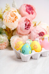 Easter Holiday background. decorative colorful Easter eggs in box and flowers on table, light background. festive Spring season. copy space. template for design