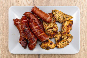 Baked sausage and chicken fillets on a traditional grill, lying on a plate.