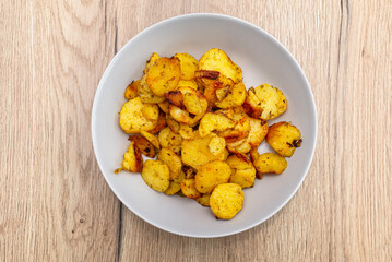 Boiled potatoes and later baked in slices on the grill, lying in a round plate.