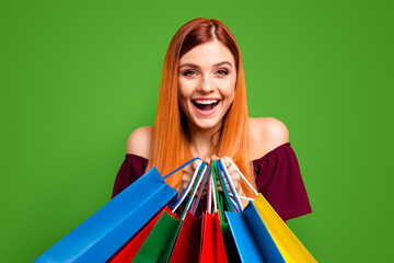 Black friday Red-haired girl laughs holding multicolored vivid shopping bags isolated on yellow background