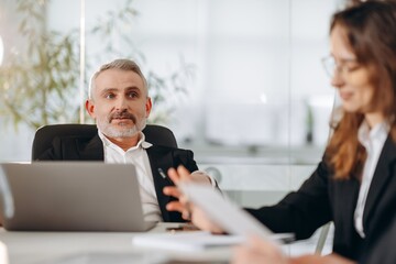 Middle-aged company ceo using laptop during conference. Selective focus of business meeting in the office