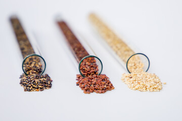 Black, red and white quinoa seeds in glass tubes on a white background. Selective focus.