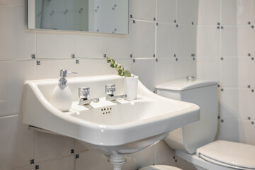 Bathroom with white tiled toilet bowl and sink with two taps and mirror in a new apartment. Concept...