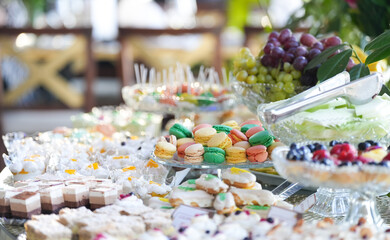 Sweets candy bar. Close up sweets photography with diferent color macarons French cuisine desert dishes at a party.