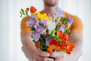 Front view of man hands giving a cute bouquet of spring flowers. Selective focus