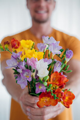 Front view of man hands giving a cute bouquet of spring flowers. Selective focus