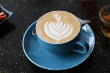 A cup of cappuccino served on an artistic black table