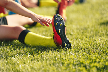 Soccer Player Stretching Legs. Football Player in Cleats Doing Stretching Exercises During Sports...