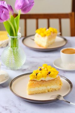 Sliced biscuit cake with cream cheese cream, lemon layer and yellow biscuit decor on a ceramic plate on a light background. Recipes for biscuit cakes.
