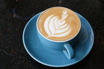 A cup of cappuccino served on an artistic black table