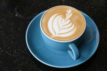 A cup of cappuccino served on an artistic black table