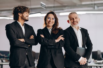 Laughing office workers in black suits having fun together. Successful business team in office. Group of businesspeople expressing positive emotions