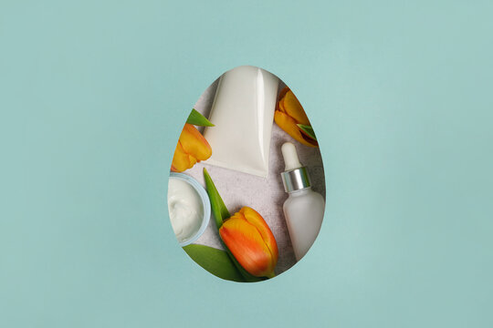 Сosmetics cream and oil with yellow tulips in an easter egg. blue background with copy space