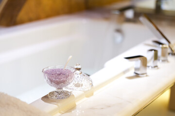 Lavender sea salt on the side of a bath tub. Lifestyle concept photo, use bath as a relaxation therapy.