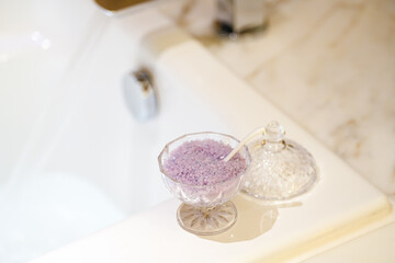 Lavender sea salt on the side of a bath tub. Lifestyle concept photo, use bath as a relaxation therapy.