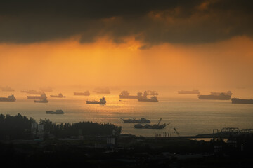 Sunrise over Singapore harbour with a lot of ships waiting on the sea line. Cargo vessel...