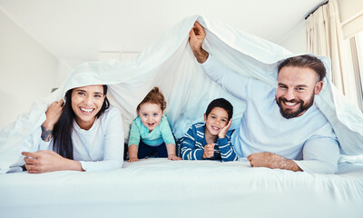 Family, portrait and blanket fort in bed with children and parents, happy and playing in their...