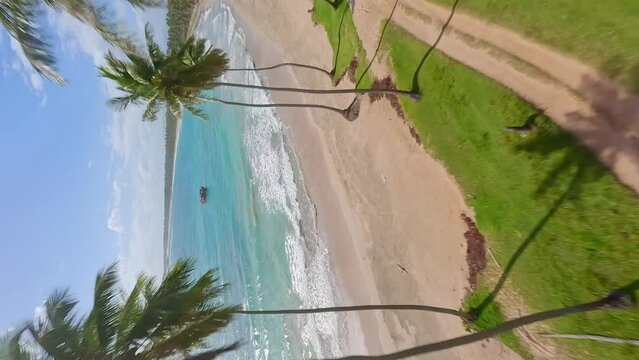 Vertical Shot Of Playa Los Coquitos With Fishing Boat On The Turquoise Water In Dominican Republic - aerial FPV
