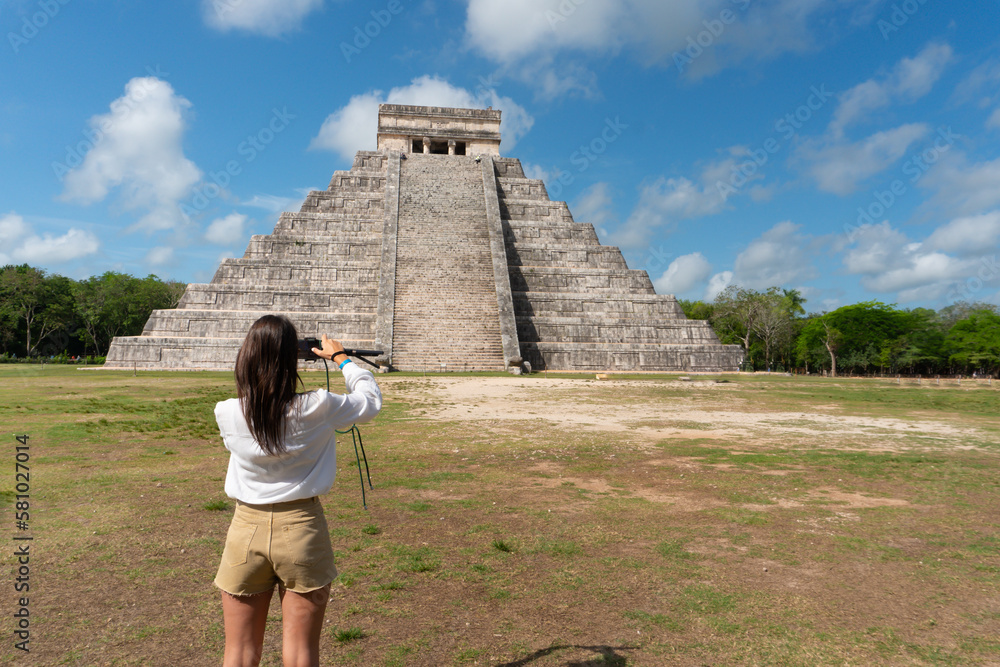 Wall mural Tourist girl in front of the background of the Kukulcan pyramid in the Mexican city of Chichen Itza. Travel concept.Mayan pyramids in Yucatan, Mexico