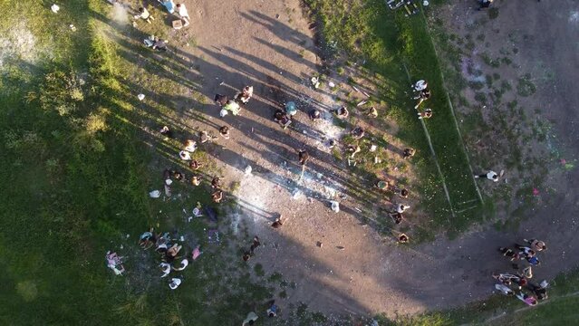 Aerial top down shot of students celebrating graduation outdoors with confetti and paint bombs