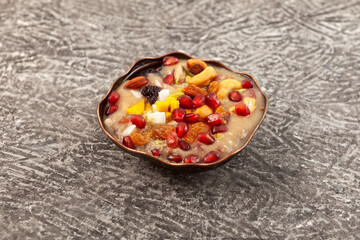 Ashure or Asura Dessert, also called as Anusabur in bowl on textured grey background, selective focus. Sweet pudding also called as Noah's pudding or Noah's Dessert